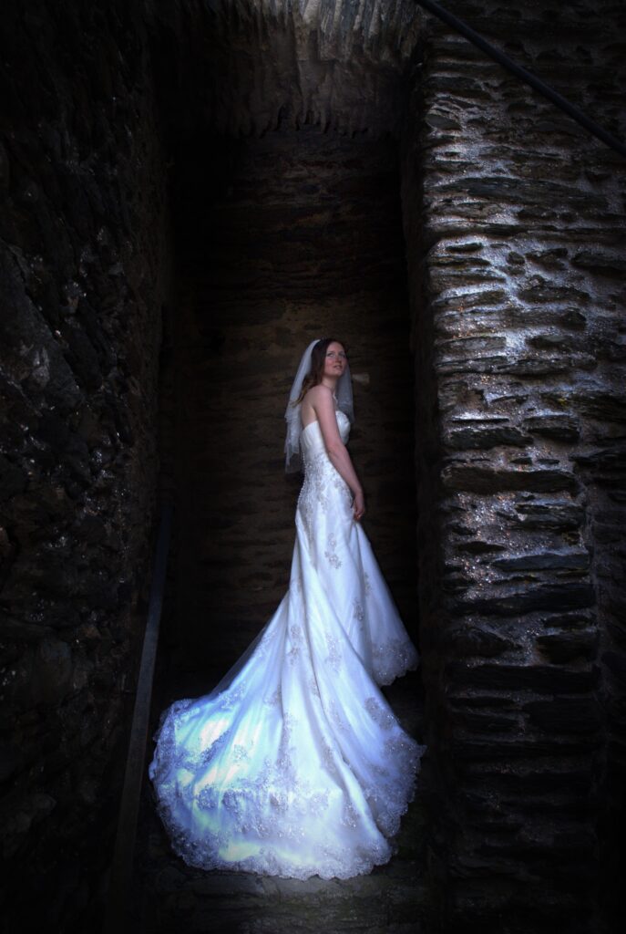 Braut steht mit ihrem Brautkleid in einem Torbogen auf Burg Hohenstein in Hessen