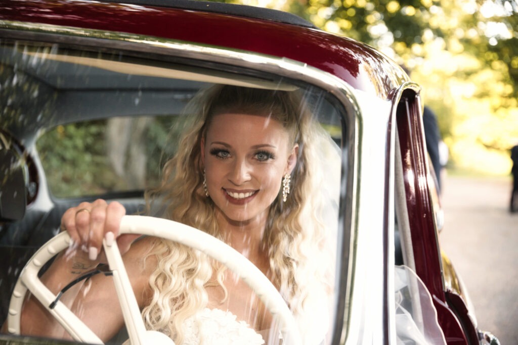 Braut sitz hinter dem Steuer eines Oldtimers