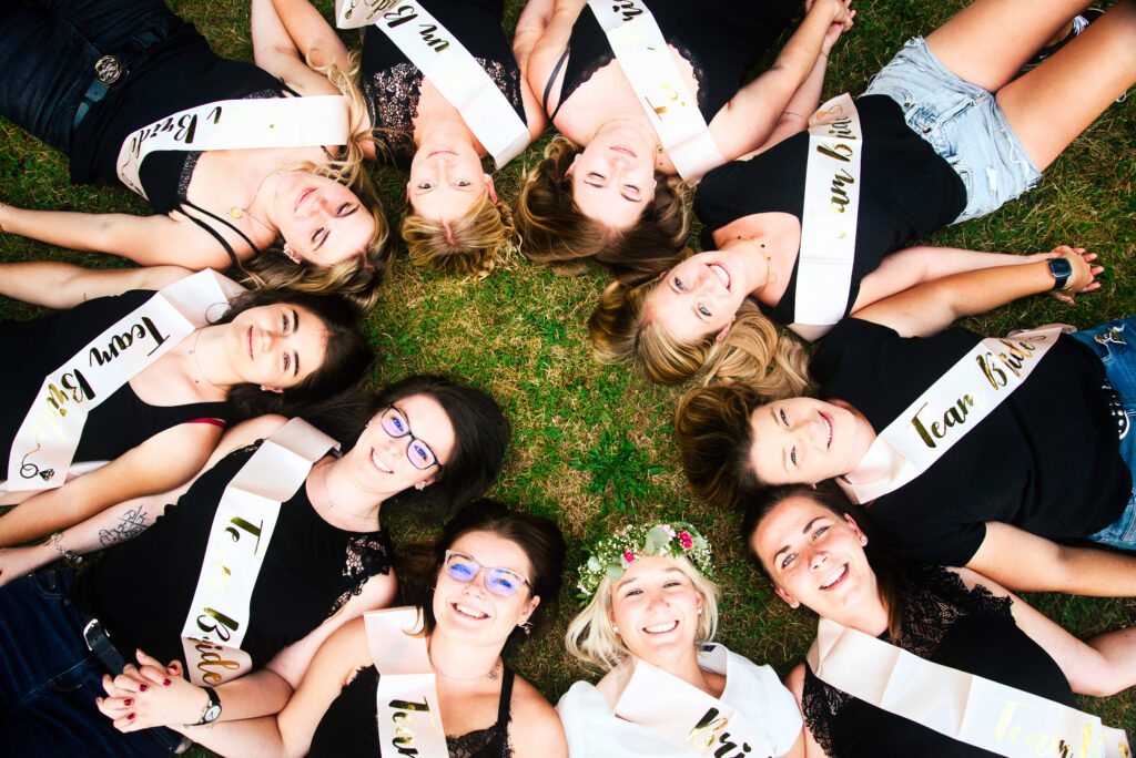 Frauen liegen auf dem Boden im Kreis die Köpfe aneinander Jungesselinen abschied und alle haben eine schleife um