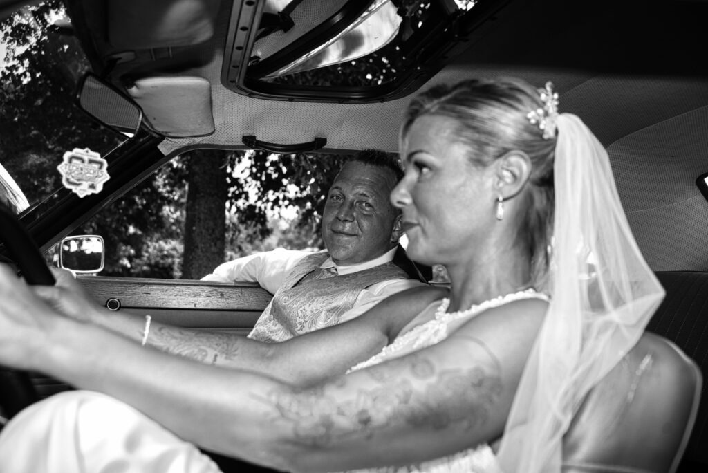 Braut und Bräutigam auf der Fahrt im Oldtimer-Hochzeitsauto